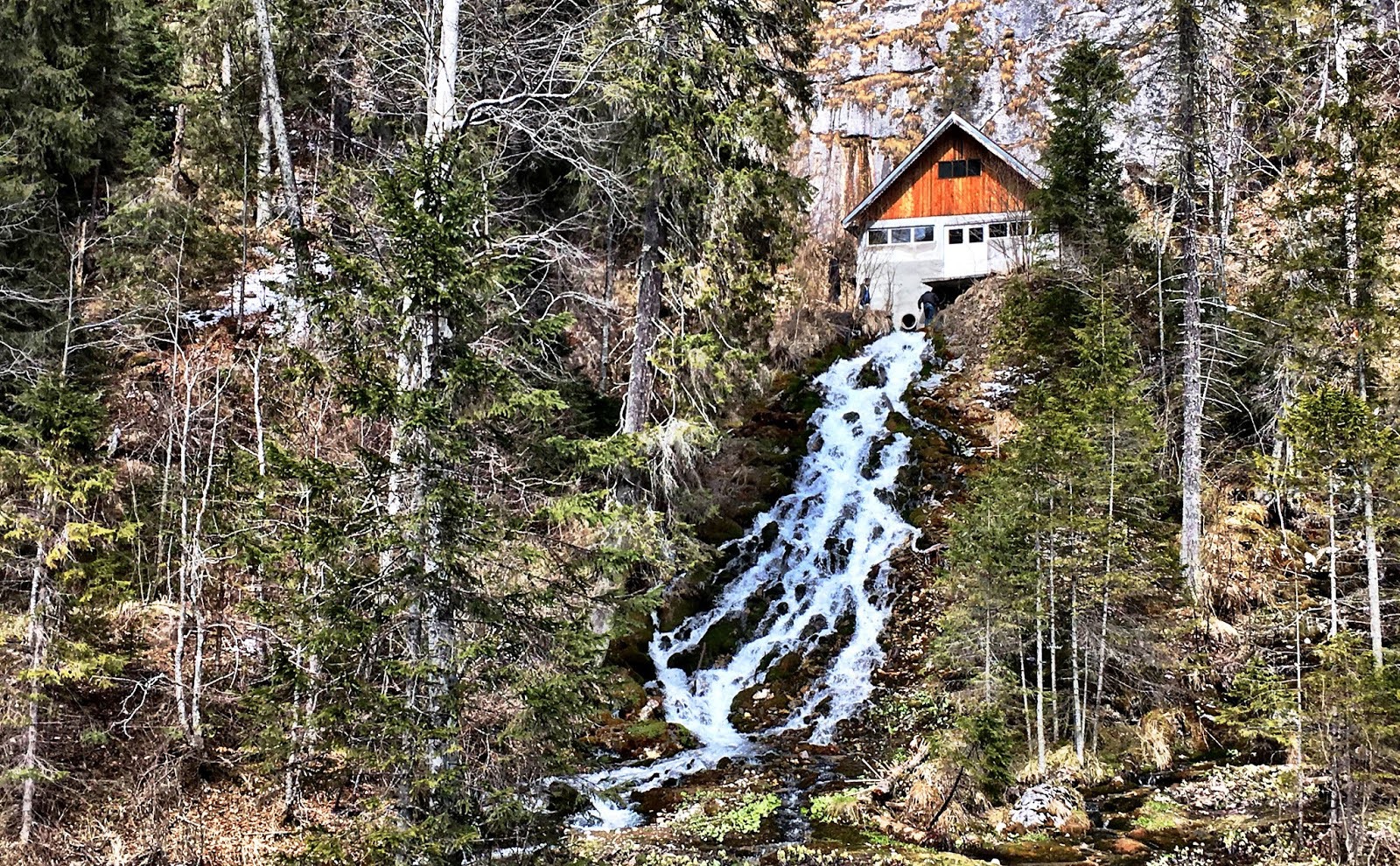 Cascada din România care curge printr-o casă. Se spune că apa ar avea puteri magice